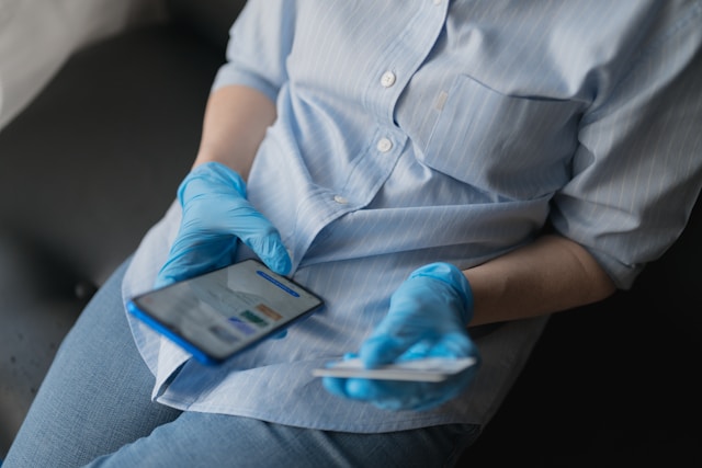 Healthcare professional holding a phone and a credit card.