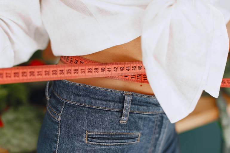 a red measuring tape around a woman’s waist