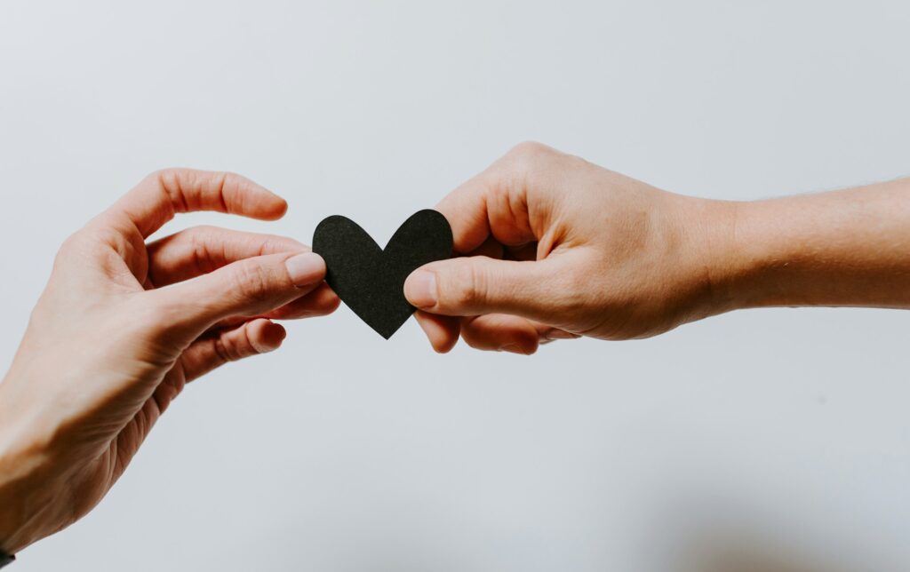 Two people holding a black paper heart.