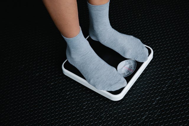 Caption: Significant weight gain or weight loss can directly impact your plastic surgery results. Alt text: A person in grey socks standing on a scale.