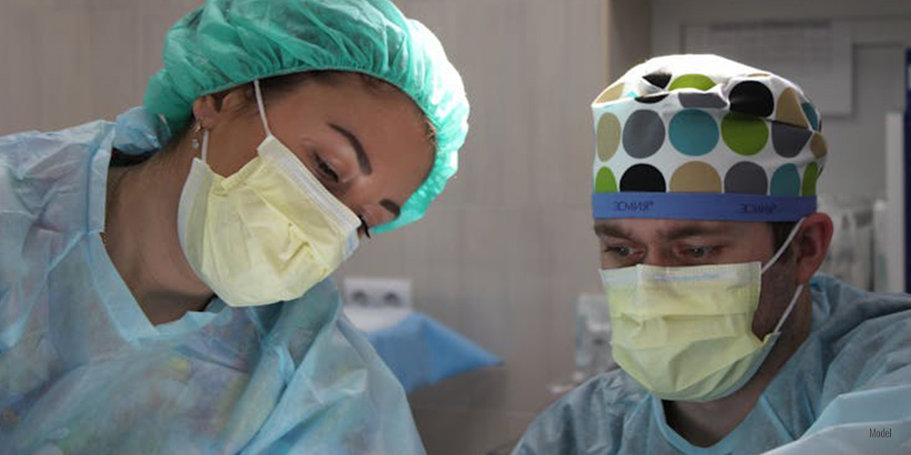 Feature image Alt text: Close-up of two surgeons with masks and caps performing a procedure.